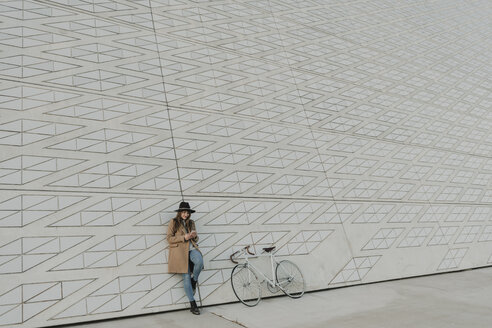 Junge Hipster-Frau hält Smartphone in der Nähe eines Fahrrads - AHSF00057