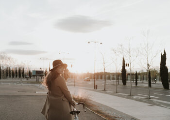 Junge Hipster-Frau fährt bei Sonnenuntergang mit dem Fahrrad - AHSF00071