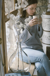Woman drinking tea witting on window sill - ALBF00820