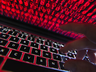 Hacker coding a computer virus infecting a laptop - ABRF00350