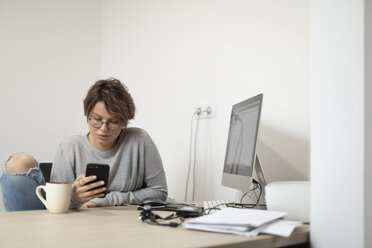Junge Frau, die zu Hause ein Smartphone benutzt, Arbeitsraum - VGF00228