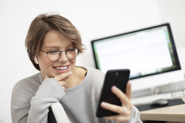 Young woman using smartphone at home, working space - VGF00229