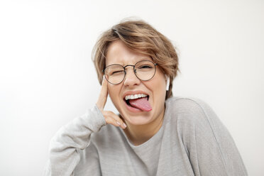 Portrait of young woman with wireless earphones pulling funny faces - VGF00233