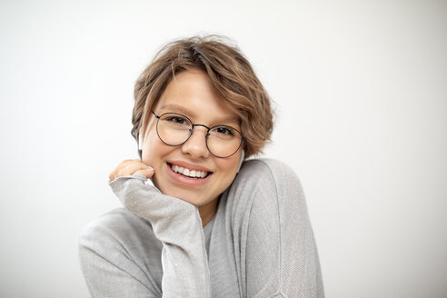 Porträt einer lachenden jungen Frau mit drahtlosen Kopfhörern und Brille - VGF00234