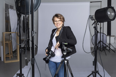 Porträt eines lächelnden jungen Fotografen mit Ausrüstung in einem Fotostudio, lizenzfreies Stockfoto