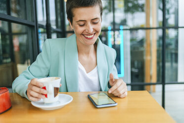 Woman in bar with mobile phone and coffee cup - KIJF02442