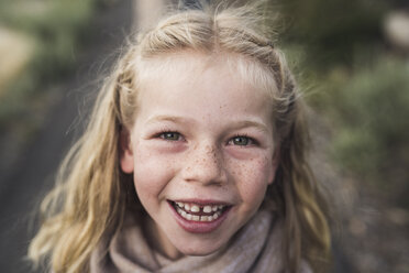 Close-up portrait of happy girl with blond hair standing in forest - CAVF63185