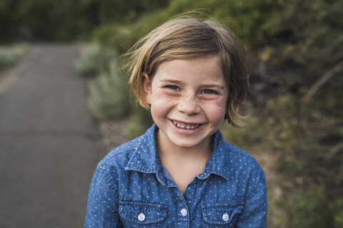 Porträt eines glücklichen Mädchens, das auf einer Straße im Wald steht, lizenzfreies Stockfoto