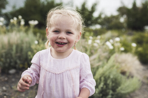 Porträt eines niedlichen glücklichen Mädchens, das gegen Pflanzen im Wald steht - CAVF63202