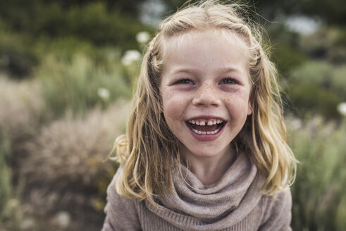 Portrait of happy girl with blond hair standing against plants in forest - CAVF63204