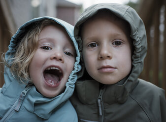 Close-up portrait of siblings in raincoats standing outdoors - CAVF63226