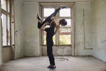 Man lifting ballerina while dancing in old building - CAVF63255