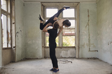 Mann hebt Ballerina beim Tanzen in altem Gebäude - CAVF63255