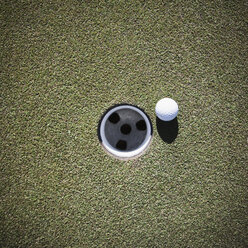 Golfball neben einem Putting Cup - MINF10874
