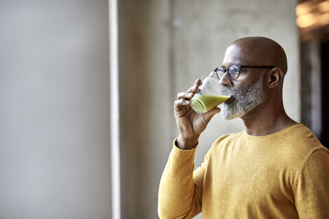 Älterer Geschäftsmann im Büro trinkt einen Smoothie, lizenzfreies Stockfoto