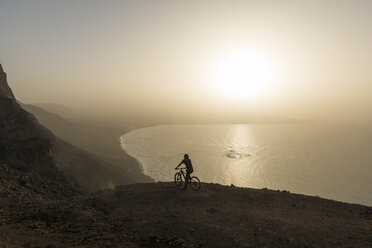 Spanien, Lanzarote, Mountainbiker auf einem Ausflug an der Küste bei Sonnenuntergang genießen die Aussicht - AHSF00104