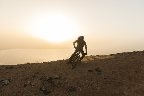 Spanien, Lanzarote, Mountainbiker bei einem Ausflug an der Küste bei Sonnenuntergang - AHSF00110