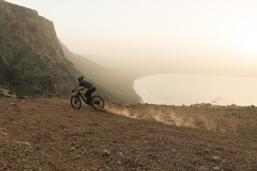 Spanien, Lanzarote, Mountainbiker bei einem Ausflug an der Küste bei Sonnenuntergang - AHSF00111