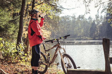Mann mit Mountainbike macht Pause an einem See im Wald - SEBF00072