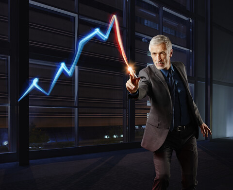 Geschäftsmann malt die Aktienmarktentwicklung mit Licht, lizenzfreies Stockfoto