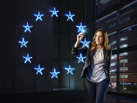 Businesswoman painting the stars of teh Europwan Union with light - RORF01797