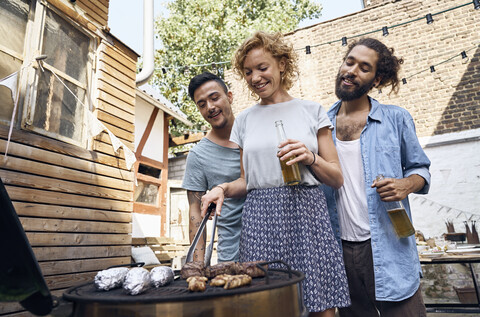 Friends having a barbecue n the backyard, preparing meat on a grill stock photo