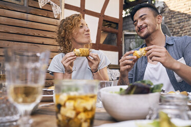 Couple eating grilled corn cobs at a backyard barbecue - PDF01857