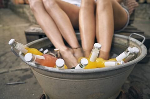Freunde entspannen sich im Sommer in einem Garten, junge Frauen kühlen ihre Füße in einer Wanne mit Getränken, lizenzfreies Stockfoto