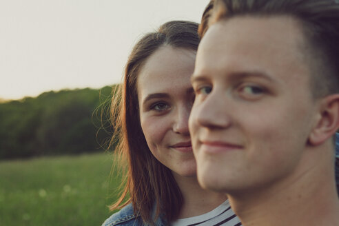 Portrait of happy teenage girl hiding behind her boyfriend - ANHF00094