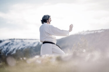 Senior man practicing karate outdoors - OCMF00303