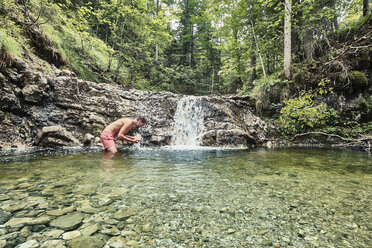 Deutschland, Oberbayern, Bayerische Voralpen, Walchensee, junger Mann steht in einem Wildbach - WFF00057