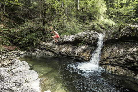 Deutschland, Oberbayern, Bayerische Voralpen, Walchensee, junger Mann springt in ein Tauchbecken, lizenzfreies Stockfoto
