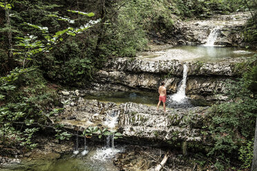 Deutschland, Oberbayern, Bayerische Voralpen, Walchensee, junger Mann steht in einem Wildbach - WFF00069