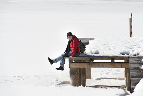 Österreich, Tirol, Achensee, Frau sitzt auf Steg im Winter - MKFF00455