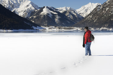 Österreich, Tirol, Achensee, lächelnde Frau am zugefrorenen See im Winter stehend - MKFF00457