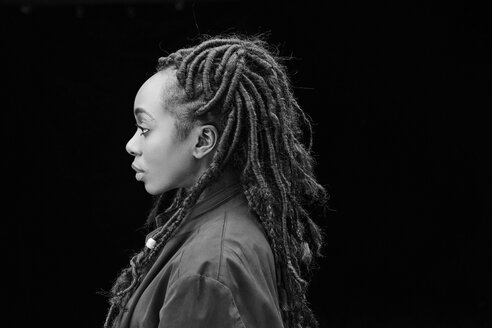 Profil einer Frau mit Dreadlocks vor einem schwarzen Hintergrund - FMKF05522
