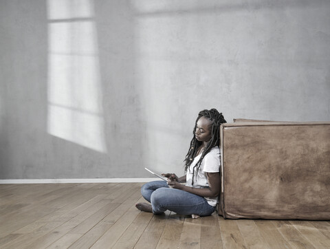 Woman sitting on the floor using digital tablet stock photo