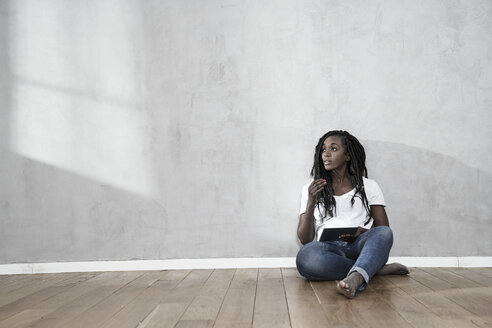 Porträt einer Frau, die mit einem digitalen Tablet auf dem Boden sitzt - FMKF05531