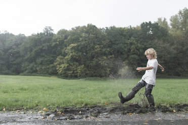 Boy splashing with dirty water of puddle - EYAF00017