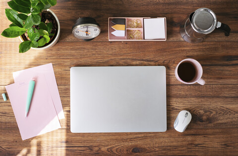 Geschlossener Laptop, Kaffeetasse und andere Utensilien auf dem Schreibtisch im Heimbüro, Draufsicht, lizenzfreies Stockfoto