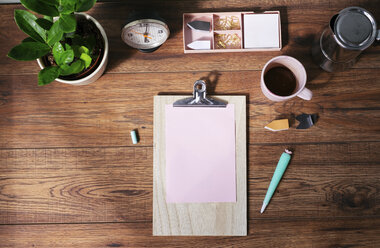 Klemmbrett mit leerem rosa Papier, Kaffeetasse und anderen Utensilien auf dem Schreibtisch im Büro zu Hause, Ansicht von oben - MOMF00637