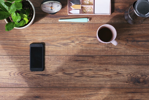 Wooden office desk with smartphone and coffee mug, top view stock photo