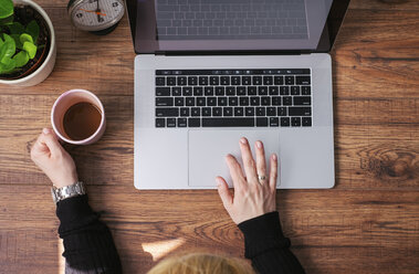 Woman working on laptop at home office, top view - MOMF00640