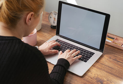 Woman working on laptop at home office - MOMF00641