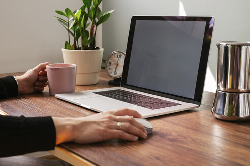 Woman working on laptop at home office, partial view - MOMF00645