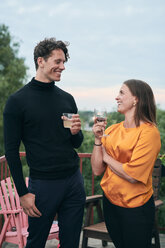 Fröhliche Freunde unterhalten sich bei einer Party auf der Terrasse mit Getränken in der Hand - MASF11558