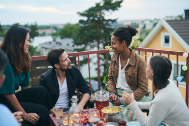 Happy friends talking while sitting on terrace during social gathering - MASF11563