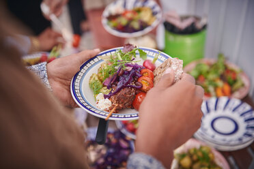 Cropped hands of woman holding meal in plate during social gathering on terrace - MASF11574