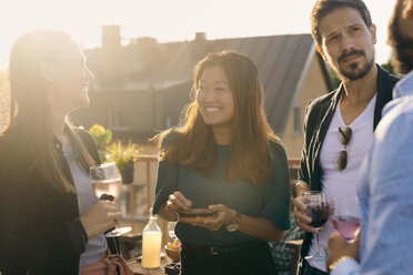 Cheerful friends having social gathering on terrace during sunset - MASF11580