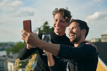 Cheerful male friends taking selfie with mobile phone on terrace - MASF11582